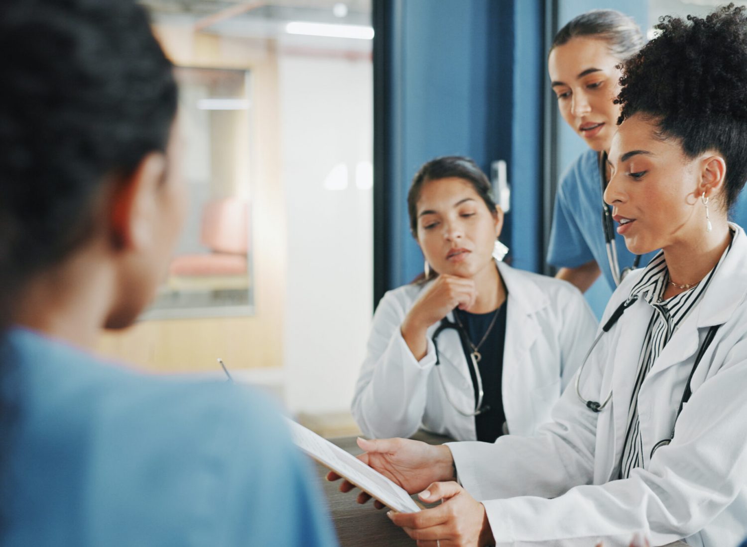 Doctors, nurse and women on clipboard in meeting, collaboration or teamwork for hospital planning, medical or life insurance. Talking, leadership and healthcare workers on paper in diversity research.